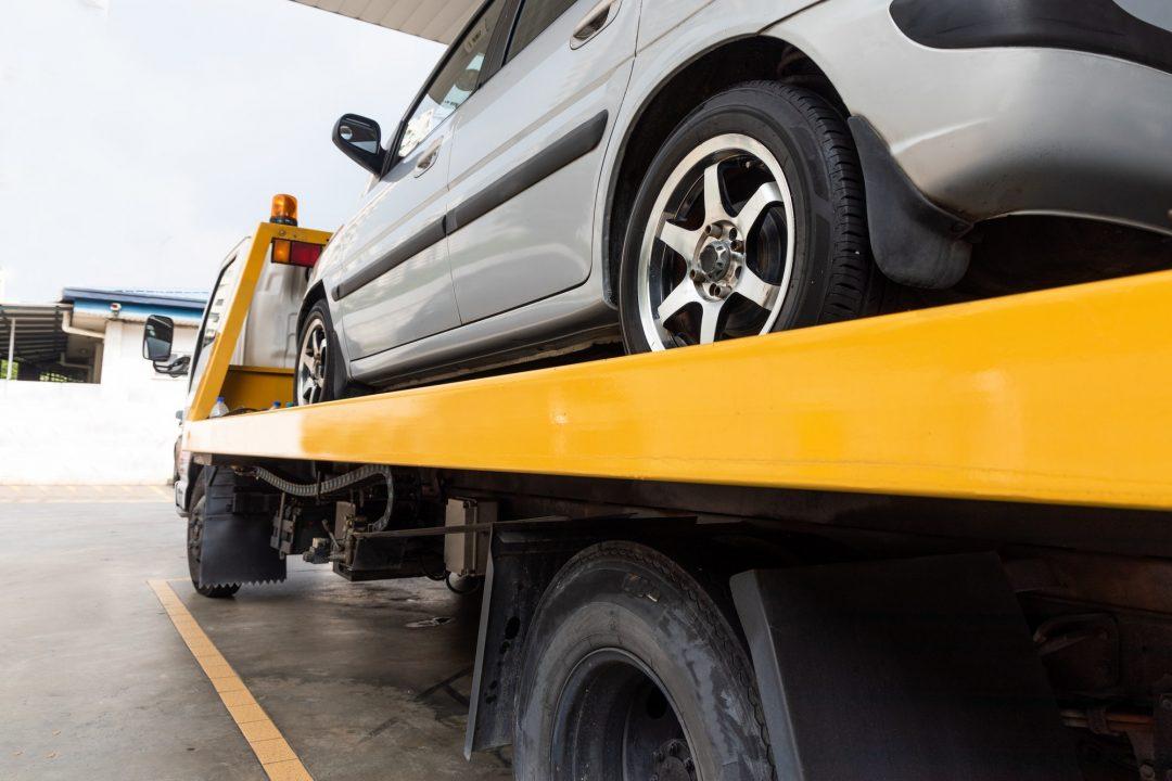 broken-car-on-flatbed-tow-truck-being-transported-for-repair.jpg